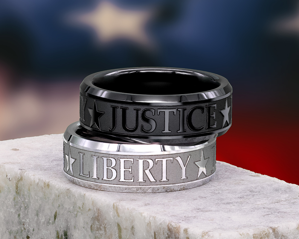 two mens rings, one serinium and one black, both showing the engraved words "JUSTICE" and "LIBERTY"