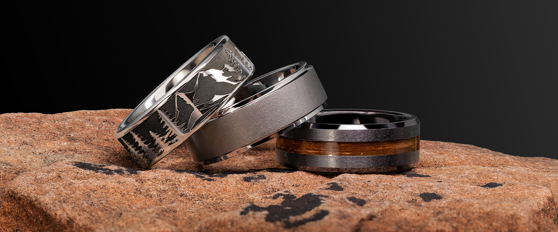 three men's rings sitting on a rock